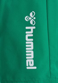 Groene stof met witte "hummeL" tekst en bijen-geïnspireerd logo, verticaal gedrukt.