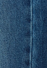 Denimová tkanina v hlubokém modrém odstínu, s diagonálním tkaním, viditelným šitím a jemnými variacemi textury, vystihující měkkost a odolnost.