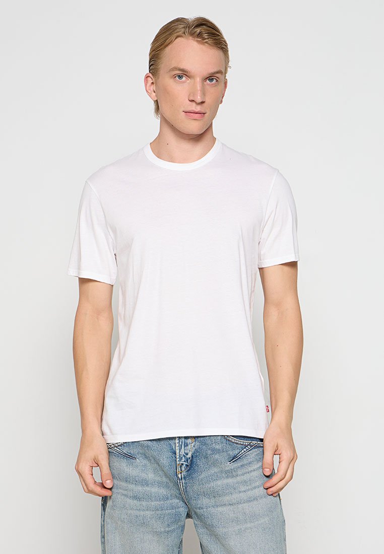 Weißes Baumwoll-T-Shirt mit Rundhalsausschnitt und kurzen Ärmeln, schlichtem Design und gerade geschnitten. Getragen mit hellblauen Jeans.