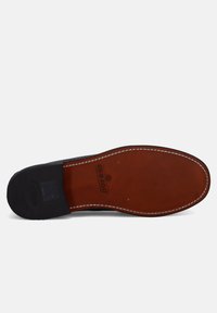 Suola in gomma nera con una soletta in pelle marrone. Presenta cuciture bianche e un logo impresso nella pelle, che mette in mostra un design di scarpa classico.