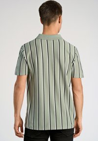 Πόλο μπλουζάκι κοντομάνικο σε ανοιχτό πράσινο χρώμα με κατακόρυφες μαύρες και λευκές ρίγες. Διαθέτει κλασικό γιακά και μαλακή υφή.