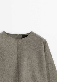 Haut à manches longues en laine grise avec encolure ronde et fermeture éclair au dos, présenté sur fond blanc.