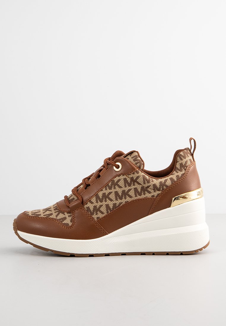 Zapatillas de cuero marrón con tejido con patrón, suela de cuña blanca y acento dorado en el talón, que presentan un cordón circular y una superficie texturizada.