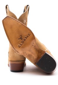 Stivali cowboy in suede color tan con ritagli a stella, tacco e sole in pelle marrone, e logo "ALDAMA" in rilievo sul tacco.