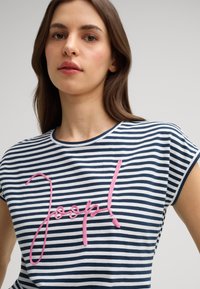 Marineblauw en witte gestreepte t-shirt met korte mouwen, voorzien van een groot roze geborduurd "Joop!" logo aan de voorkant. Zacht katoen materiaal.