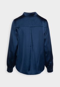 Mørkeblå satinbluse med lange ærmer, plissee-detalje på ryggen og knaplukning ved håndleddene, vist fra ryggen.