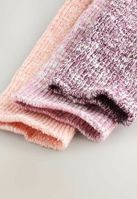 Tričko pletené šály v rôznych odtieňoch ružovej a fialovej, s textúrovanými vzormi a strapcovými okrajmi, naukladané na svetlom pozadí.
