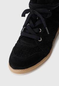 Must värvi sametised tennisesuusad tekstuursete detailidega, ümarate varvastega, mustade paeltega ja kummist väliskattega, millel on ziku-zaku muster.