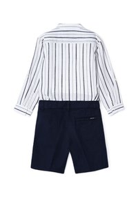 Camicia a maniche lunghe a righe bianche e blu abbinata a pantaloni corti blu su misura. La camicia presenta bottoni e dettagli sui polsini; i pantaloni corti hanno una tasca sul retro.