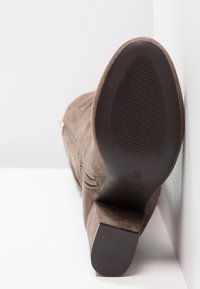 Brown suede ankle boot with a textured sole, side zipper, and a modest heel. The interior features a smooth lining. Size marked as 39.