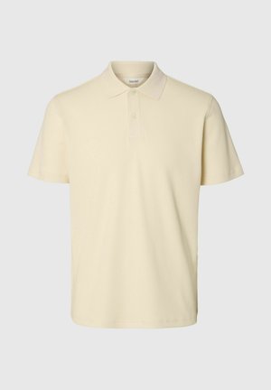 Bež kratka polo majica s klasičnim ovratnikom i patentom s dva gumba, izrađena od teksturiranog materijala.
