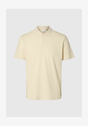 Bež kratka polo majica s klasičnim ovratnikom i patentom s dva gumba, izrađena od teksturiranog materijala.
