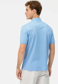 Polo shirt blu chiaro in morbido misto cotone, maniche corte, aperture laterali all'orlo e design del colletto classico. Vista dal retro mostrata.