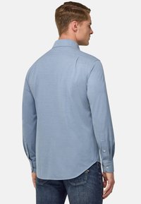 Camicia a maniche lunghe azzurro chiaro, con polsini abbottonati, dettaglio sullo yoke posteriore e orlo arrotondato. Tessuto morbido, design casual. Adatta per varie occasioni.