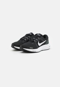Black athletic shoes with mesh upper, contrasting white Nike logo, laced closure, textured rubber sole, and cushioning detail on the heel.