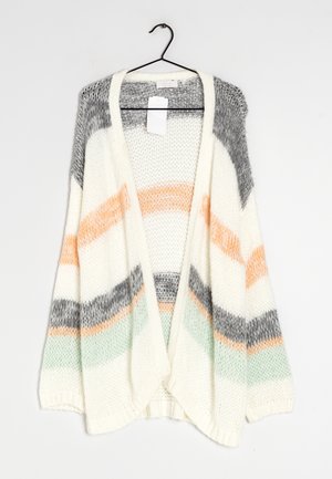 Gruby kardigan na drutach z szerokimi paskami w kolorze szarym, brzoskwiniowym i miętowym, zawieszony na czarnym wieszaku na białym tle.