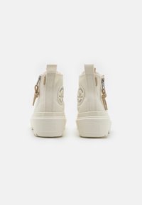 Kremowe kozaki za kostkę z zamkiem błyskawicznym, z okrągłą naszywką logo oraz teksturowaną białą gumową podeszwą. Pętla do łatwego zakładania.