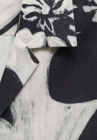 Stoff mit floralem Muster in Schwarz-Weiß, das durch kräftige Pinselstriche, eine strukturierte Oberfläche und einen weichen Fall besticht.