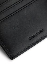 Czarny portfel wykonany z prawdziwej skóry ma teksturowaną powierzchnię, liczne sloty na karty oraz wytłoczone napisy. Krawędzie są przeszyte dla zwiększenia trwałości.