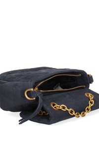 Sac à main en daim noir avec un design matelassé, une bandoulière en chaîne dorée, une fermeture à glissière et deux compartiments pour le rangement.