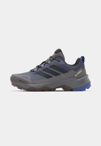 Chaussures de randonnée grises et bleues présentant une tige en maille et synthétique, une semelle texturée, un laçage prononcé et trois bandes noires sur le côté.