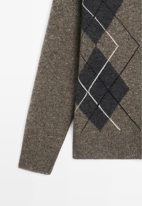 Brązowy rękaw swetra z dzianiny z szarym, czarnym i białym wzorem rombów w stylu argyle oraz ściągaczem na mankiecie i dole.