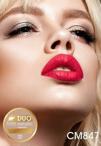 Kokie metallisk ögonskugga i Haze, visad nära läpparna. Närbilden visar djärva röda matta läppar, skimrande guldögonskugga och en jämn hudstruktur.