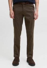 Pantalones de algodón marrón con un corte recto, que presentan una textura suave y un cinturón. Combinados con zapatos marrón oscuro.