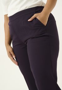 Pantaloni stretch blu marina con una texture liscia e una vita elastica, dotati di tasche laterali e una vestibilità su misura.