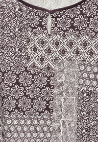 Mønstrede stoffer med fire forskellige designs: blomstermotiv, geometriske og abstrakte former i hvide og mørkelilla nuancer, med en knaplukning ved halsudskæringen.