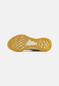 Suela de zapato con un patrón de banda amarilla, que presenta formas texturizadas variadas y un logotipo visible de Nike Running en el centro.