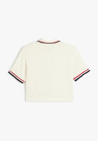Polo shirt crema a maniche corte con tessuto testurizzato, strisce contrastanti rosse e blu navy su colletto e maniche. Design semplice e squadrato.