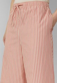 Shorts en coton rayés rose et crème avec une taille élastique et un cordon de serrage. Comprend des poches latérales et une coupe décontractée.