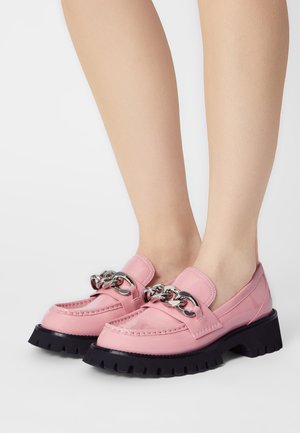 Mocasines de cuero rosa con acentos de cadena plateada, con puntera redondeada, suela gruesa negra y detalles de costura visibles.