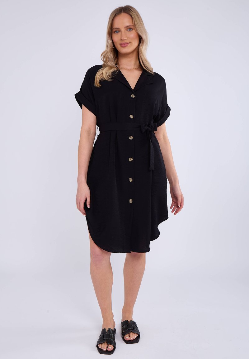 Abito camicia nero con maniche corte, chiusura a bottoni sul davanti e cintura in vita. Tessuto morbido con orlo sagomato e spacchi laterali.