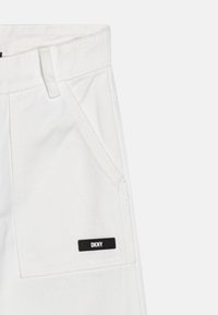 Hvite jeansshorts med frontlomme, svart DKNY-merke, rett snitt og kontrasterende sømdetaljer.