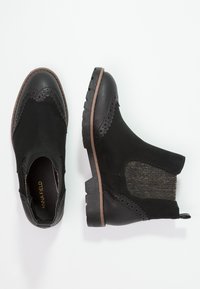 Bottines noires en mélange de suède et de cuir. Présentent des perforations décoratives, des panneaux latéraux élastiques et une semelle texturée.