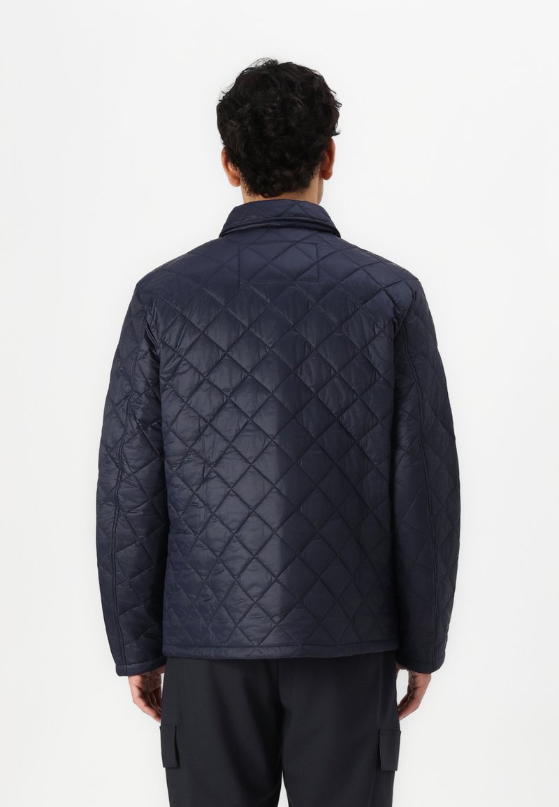 Veste matelassée marine avec un motif en diamants, dotée d'un col et de manches longues. Matière lisse et brillante. Design simple sans embellissements.