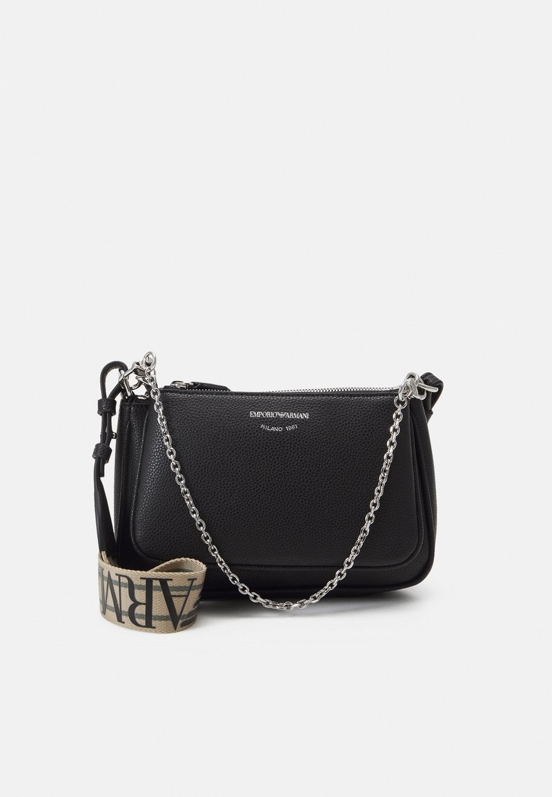 Černá kožená crossbody taška s texturovaným povrchem, stříbrným řetízkovým popruhem a látkovou rukojetí s výrazným písmem. Zapínání na zip.