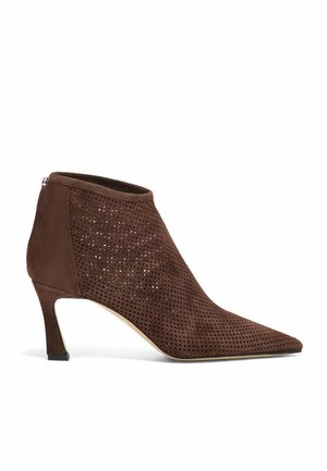 Stivaletto in camoscio marrone con design traforato, punta appuntita e tacco di 5 cm. Chiusura laterale con cerniera e texture liscia che valorizza la silhouette.