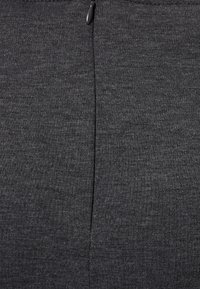 Dunkelgrauer Stoff mit einer glatten Textur, der eine Mittelnaht und einen kleinen Reißverschluss oben zur Schließung aufweist. Schlichtes Design, keine Muster.