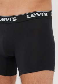 Fekete pamut boxer short, márkázott elasztikus derékpánttal, rajta fehér "Levi's" felirattal. Sima textúra, testhezálló kialakítás és combközép hossz.