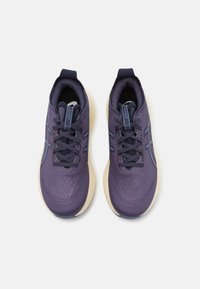 Chaussures de sport violettes avec un dessus texturé, des accents bleus et des lacets noirs. Elles possèdent une semelle rembourrée et un col rembourré pour le confort.