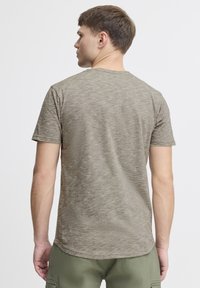 Olivenfarvet t-shirt med korte ærmer og tekstureret mønster, med en rund halsudskæring og en lidt længere bagkappe.