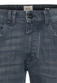 Slim-fit denim jeans in donkerblauw met een vervaagd textuur, vijf zakken en een zwarte knoopsluiting bij de tailleband. Camel Active-label zichtbaar.