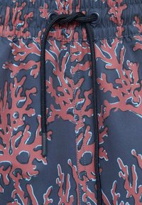 Plavalne hlače, ki vključujejo temno tkanino s koralnim vzorcem v rdečih in modrih odtenkih, elastičen pas in črno vrvico.