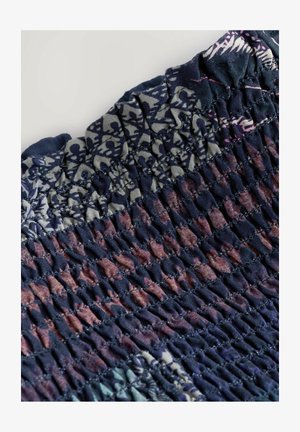 Smockstoff mit einem mehrfarbigen Blumenmuster, das dunkle Blautöne, Purpur und Pink enthält. Texturierte Oberfläche mit gerafften Details.