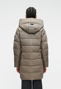 Dlhý, polstrovaný kabát svetlohnedej farby, s kapucňou, horizontálnym prešívaním a štíhlym dizajnom. Zadný pohľad ukazuje hladkú textúru a štruktúru.