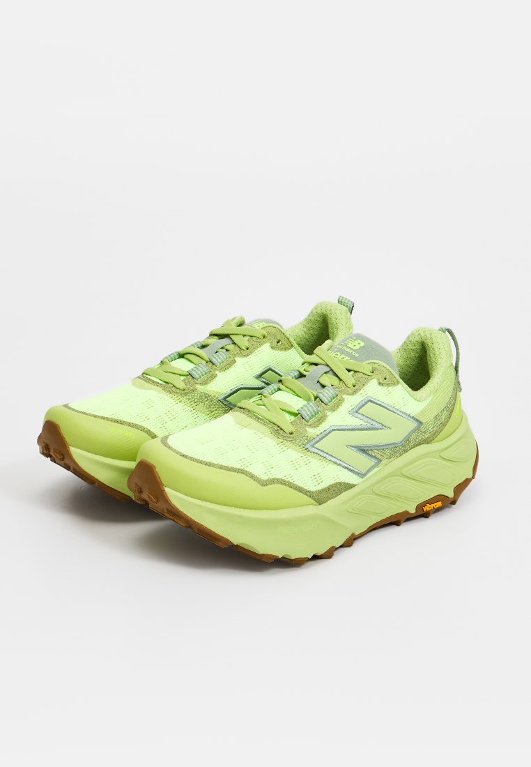 Par de zapatillas de running New Balance de color verde claro con suelas gruesas de goma marrón y logo gris en los lados sobre fondo blanco.