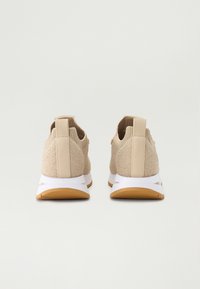 Beige sportieve schoenen met een gestructureerde gebreide bovenkant, witte tussenzool en rubberen outsole. Voorzien van een lipje aan de hiel voor gemakkelijke aan- en uittrekken.